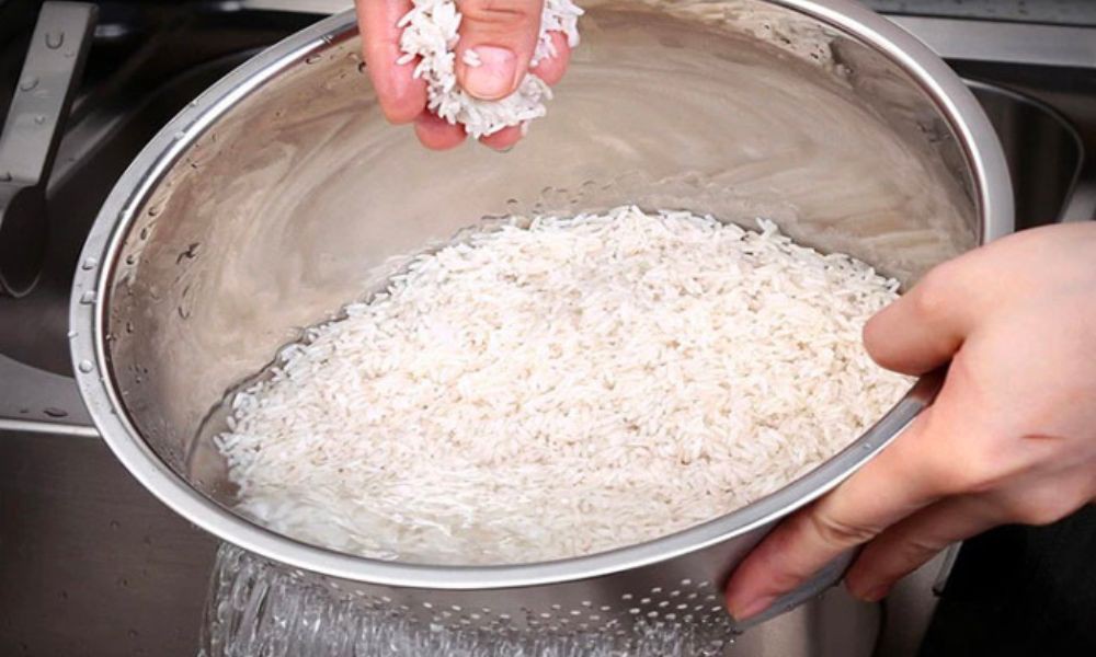 cho gạo vào nồi bằng cách bốc từng nắm gạo